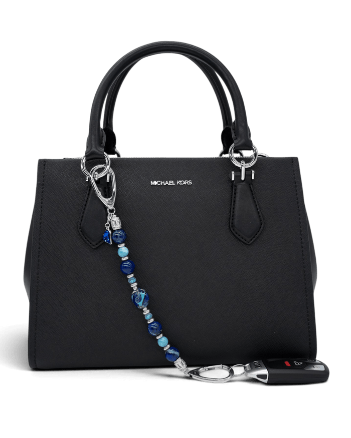 LD Keyfinder Sapphire Allure beaded accessory with blue gemstones and glass charms attached to a black handbag.