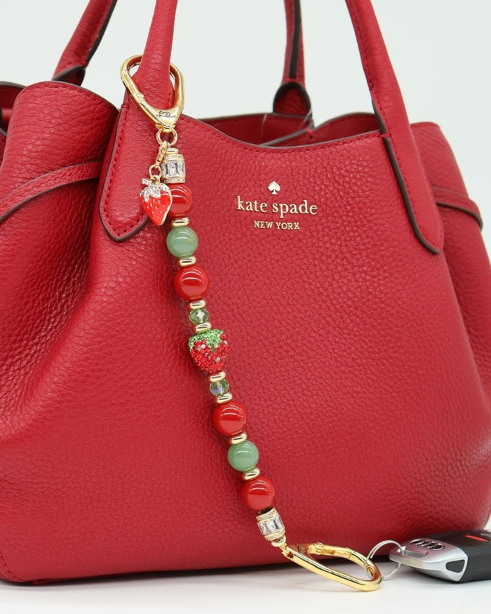 LD Keyfinder Strawberry Fields beaded accessory with red shell pearls, green aventurine, and crystal strawberry charm.