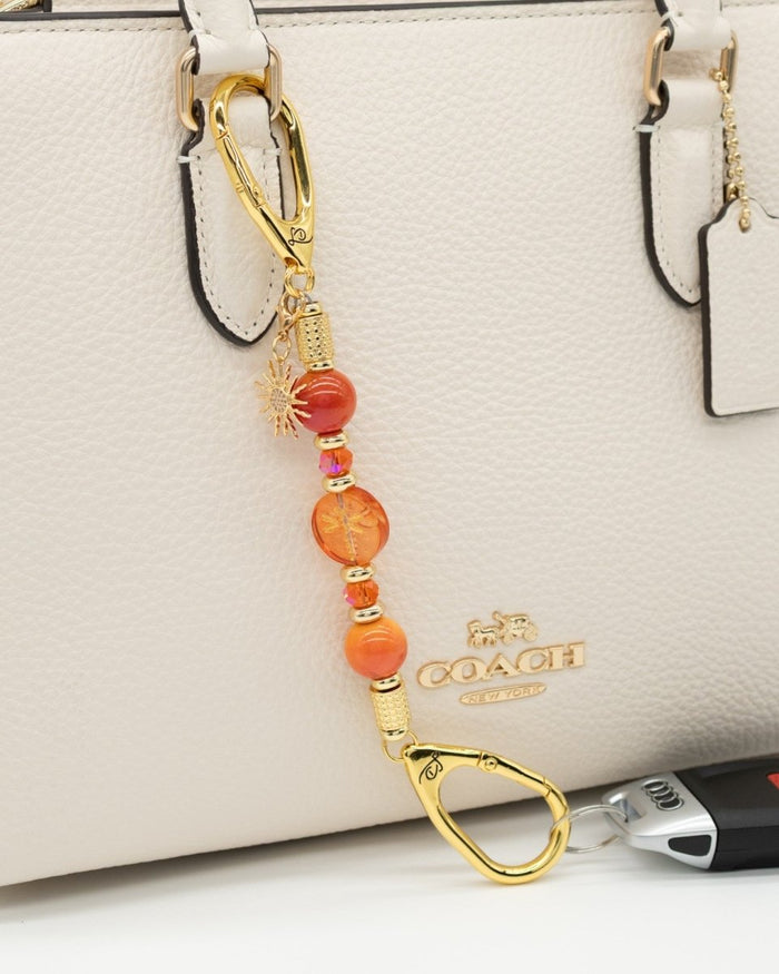 LD Keyfinder Summer Sunset Mini beaded keychain with coral glass dragonfly, orange agate, and gold sun charm on a bag