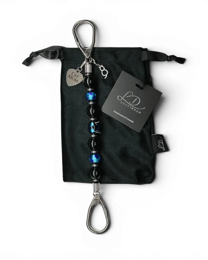 LD Keyfinder Whisker Dreams beaded keychain with black obsidian, blue foil glass, and Cat Mom charm on velvet bag