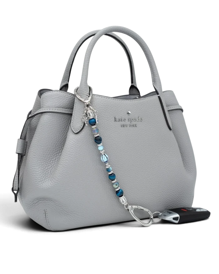 LD Keyfinder Whispering Garden beaded keychain with blue glass tulip, tiger eye, and charms attached to a grey handbag